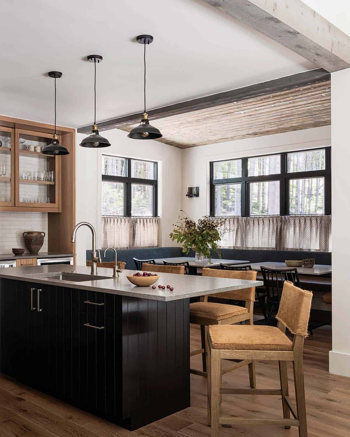 Kitchen and dining nook with black island, pendant lights, tongue-and-groove ceiling, and U-shaped banquette, Greenwater, Washington