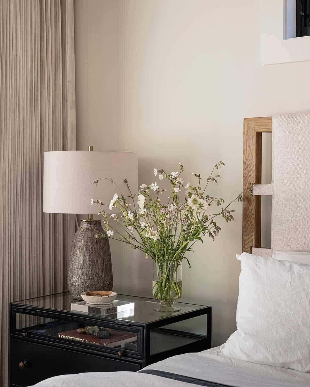 Bedroom nightstand detail with ceramic lamp, wildflower bouquet, and oak headboard, Greenwater, Washington