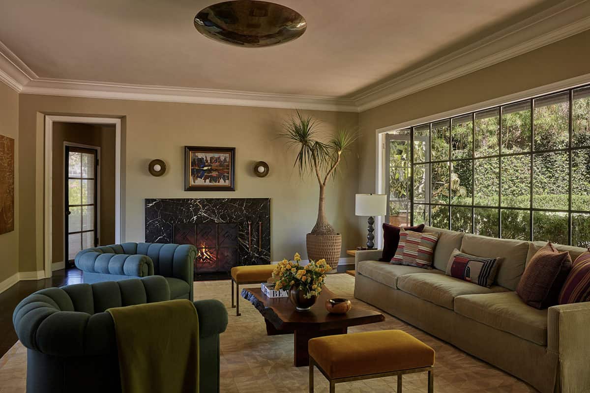 Living room with marble fireplace, channeled blue sofa, and steel windows, Los Feliz colonial revival home