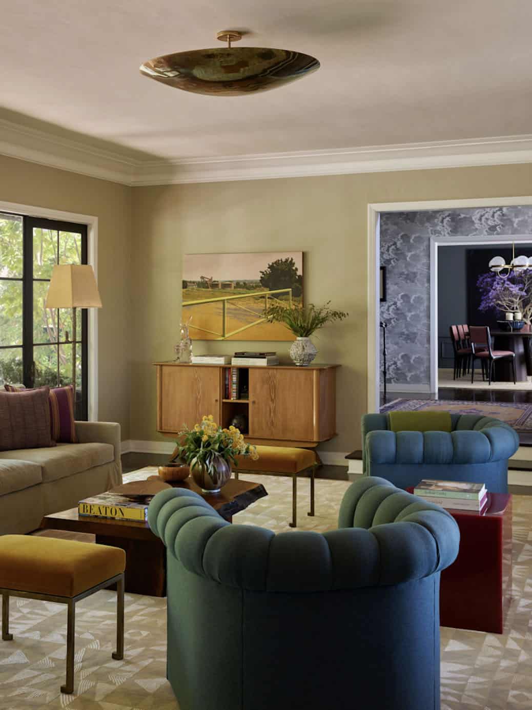 Living room with teal channeled sofas and view into dark dining room, Los Feliz colonial revival home