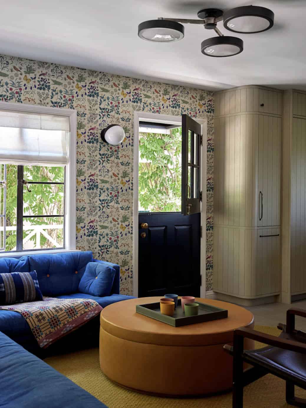 Family room with blue sofa, botanical wallpaper, and built-in storage, Los Feliz colonial revival home