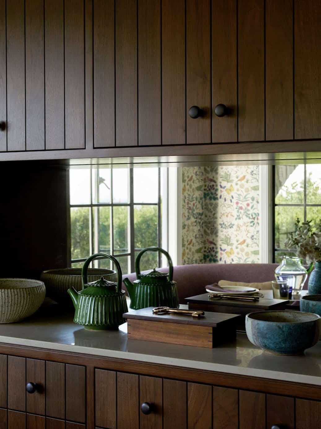 Kitchen counter detail with dark wood cabinetry and green ceramic teapots, Los Feliz colonial revival home