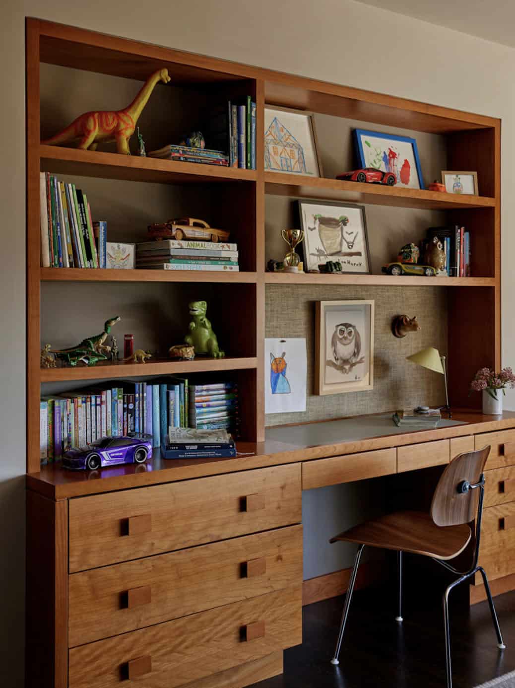 Built-in walnut shelving with integrated desk, children's artwork, and Eames chair, Colonial Revival home by Commune Design
