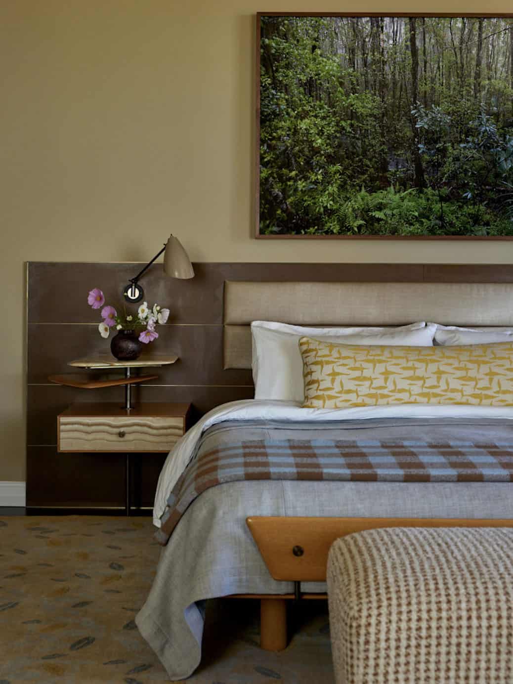 Primary bedroom detail with upholstered headboard, onyx nightstand, plaid blanket, and botanical artwork, Los Feliz home by Commune Design
