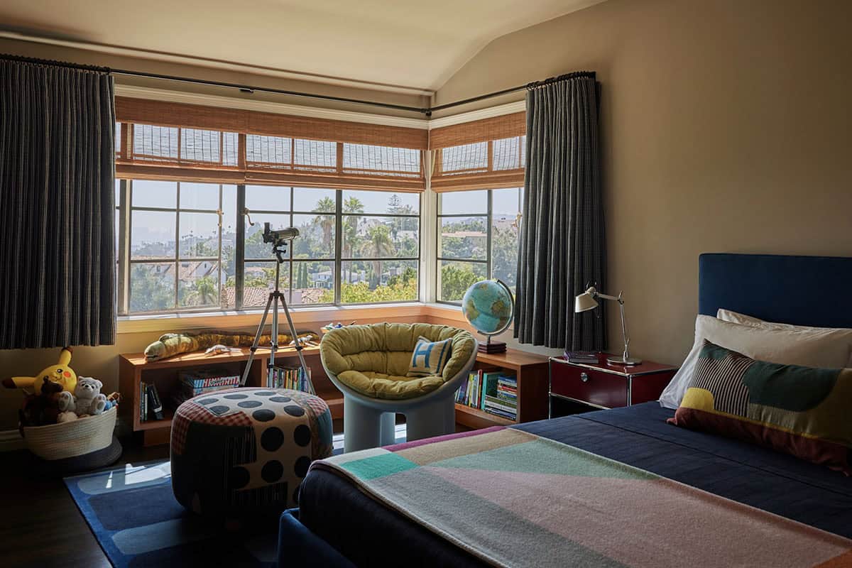 Children's bedroom with navy headboard, colorful blanket, corner windows, telescope, and Los Angeles views, Los Feliz, California