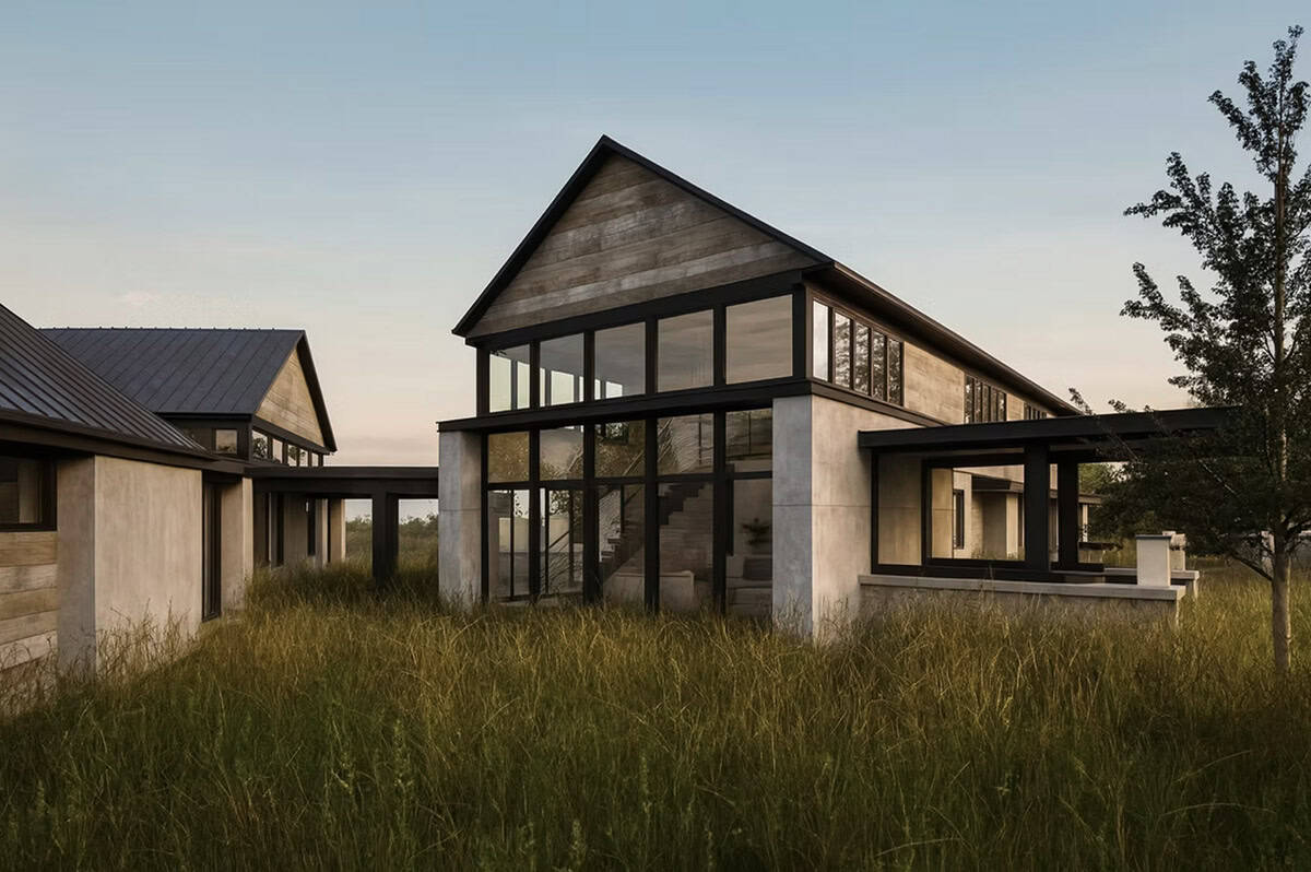 Contemporary home exterior with floor-to-ceiling black framed windows and weathered wood siding overlooking natural meadow in Hudson Wisconsin