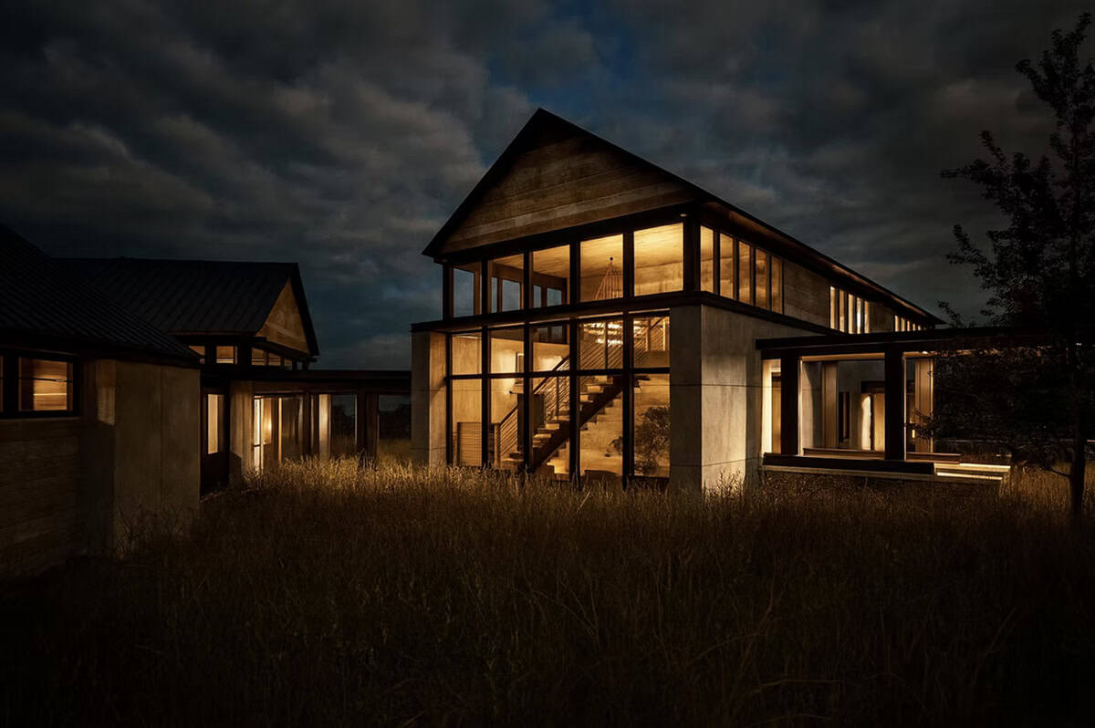 Contemporary home exterior at night with illuminated staircase and floor-to-ceiling black framed windows in Hudson Wisconsin