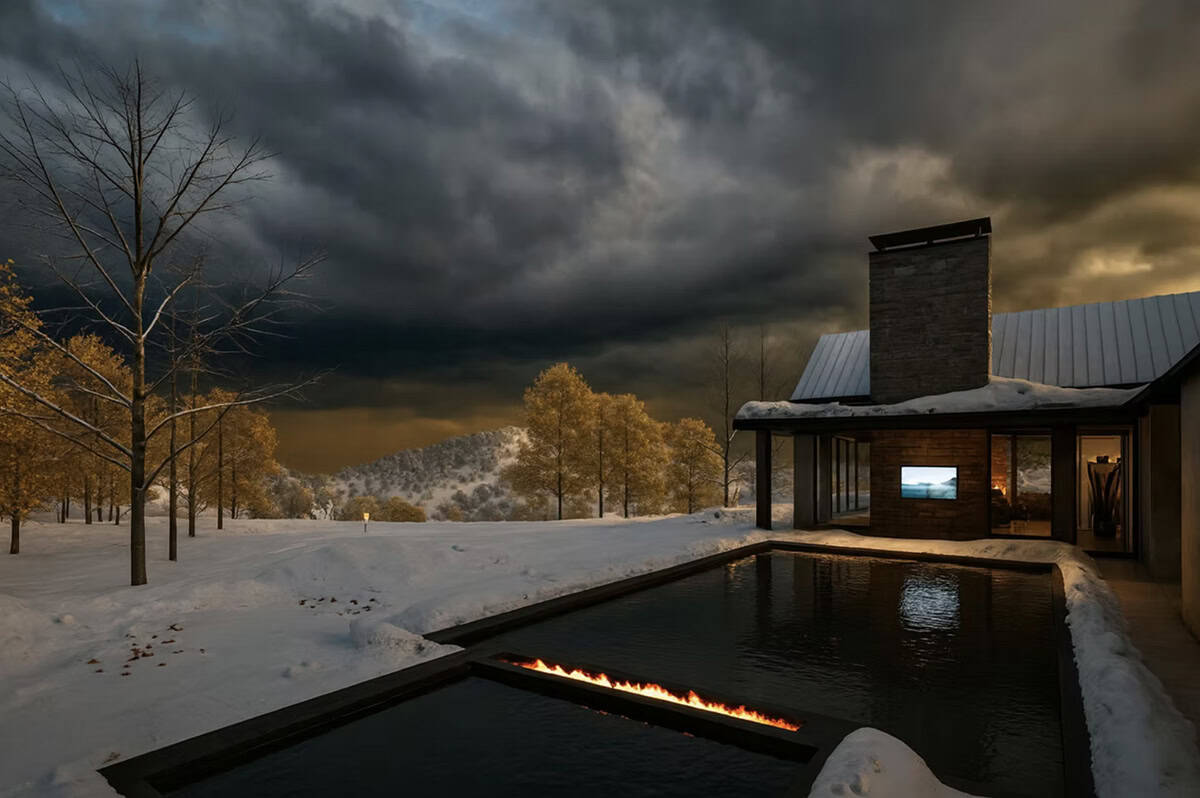 Contemporary home pool and fire feature in winter snow with stone chimney and dramatic stormy sky in Hudson Wisconsin