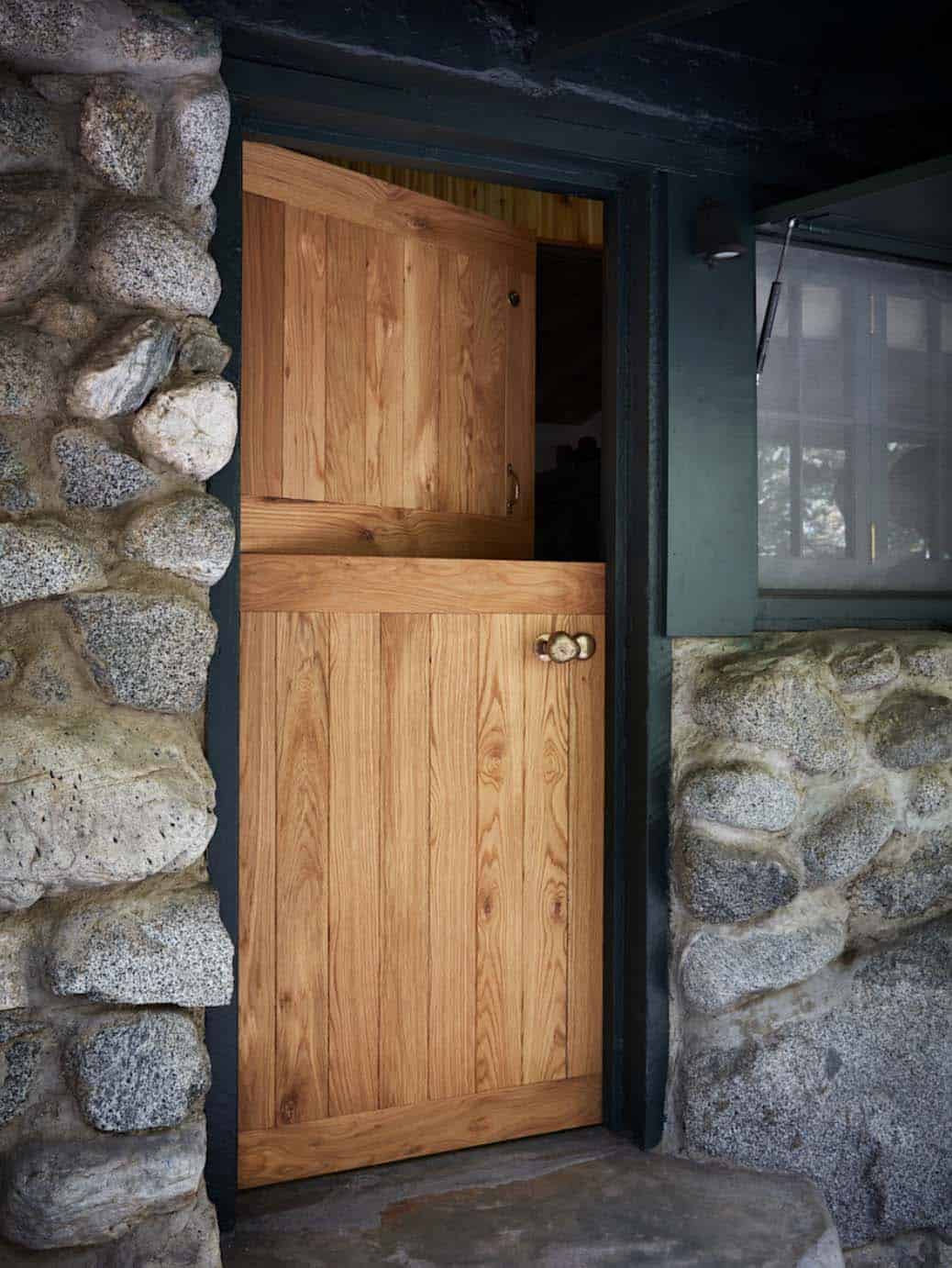 Custom solid white oak Dutch door with brass hardware set in original stone wall