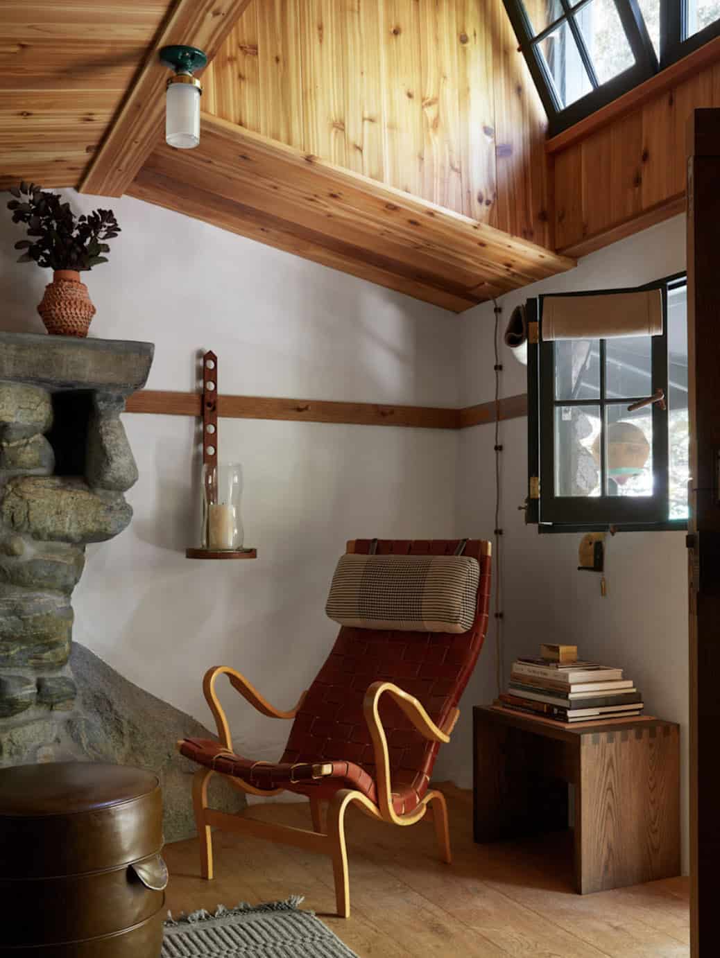 Leather lounge chair beside original stone fireplace with knotty pine ceiling and skylight