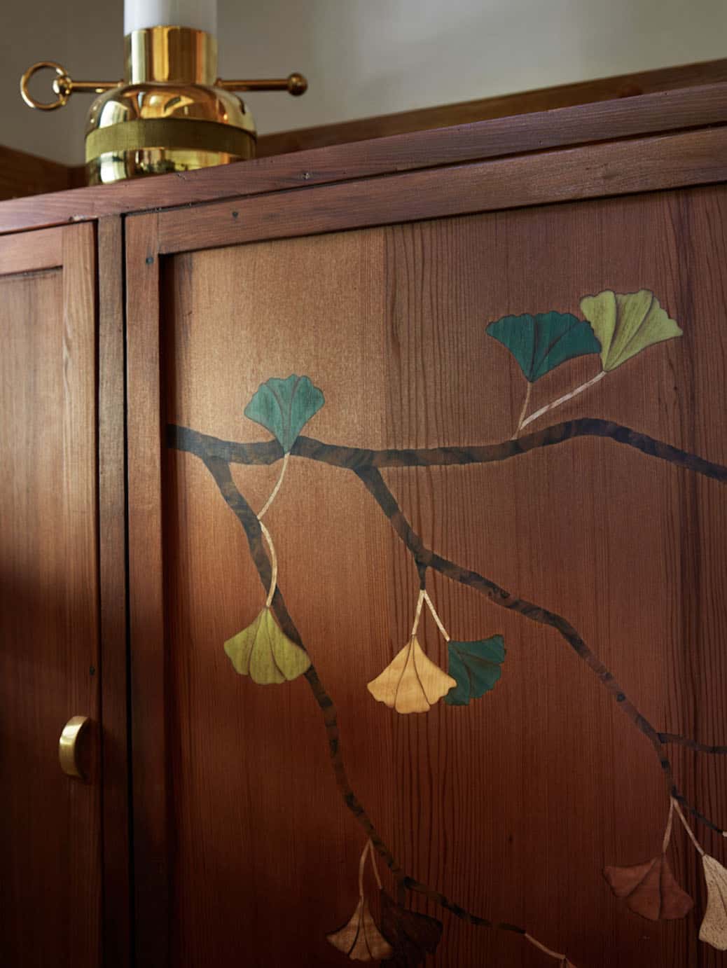 Close-up detail of custom ginkgo leaf marquetry on reclaimed redwood armoire