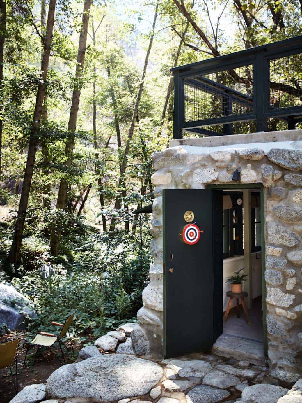 Stone exterior of historic canyon cabin with dark green door and boulder pathway