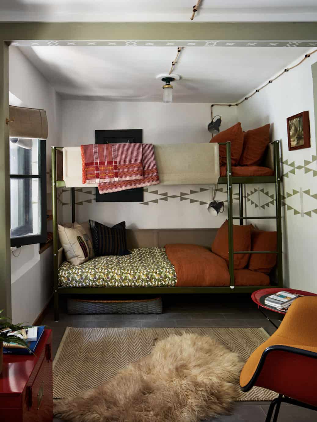 Bunk room with olive green metal bunk beds and hand-painted geometric wall pattern