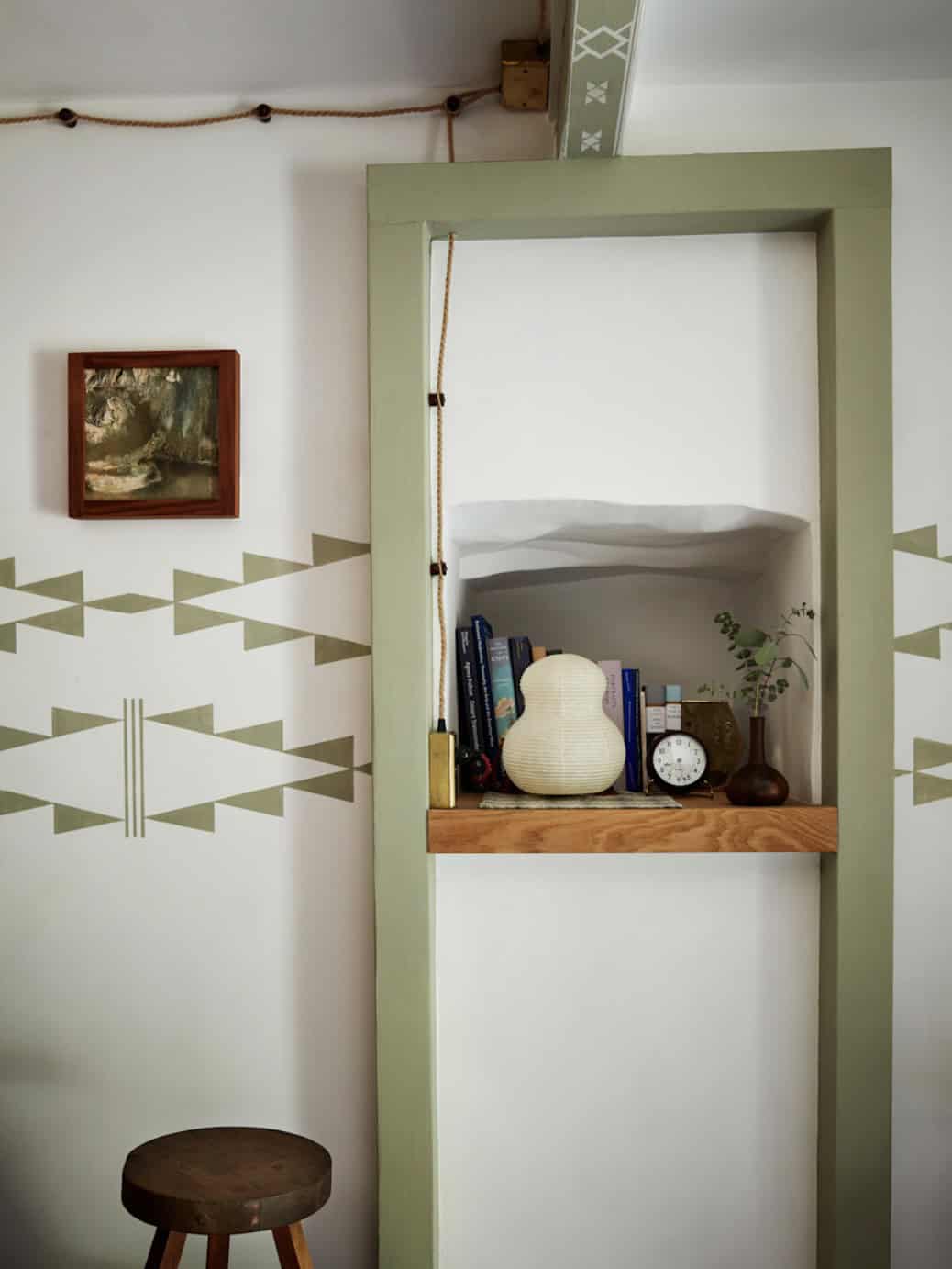 Bunk room with hand-painted geometric wall pattern and built-in green shelf niche