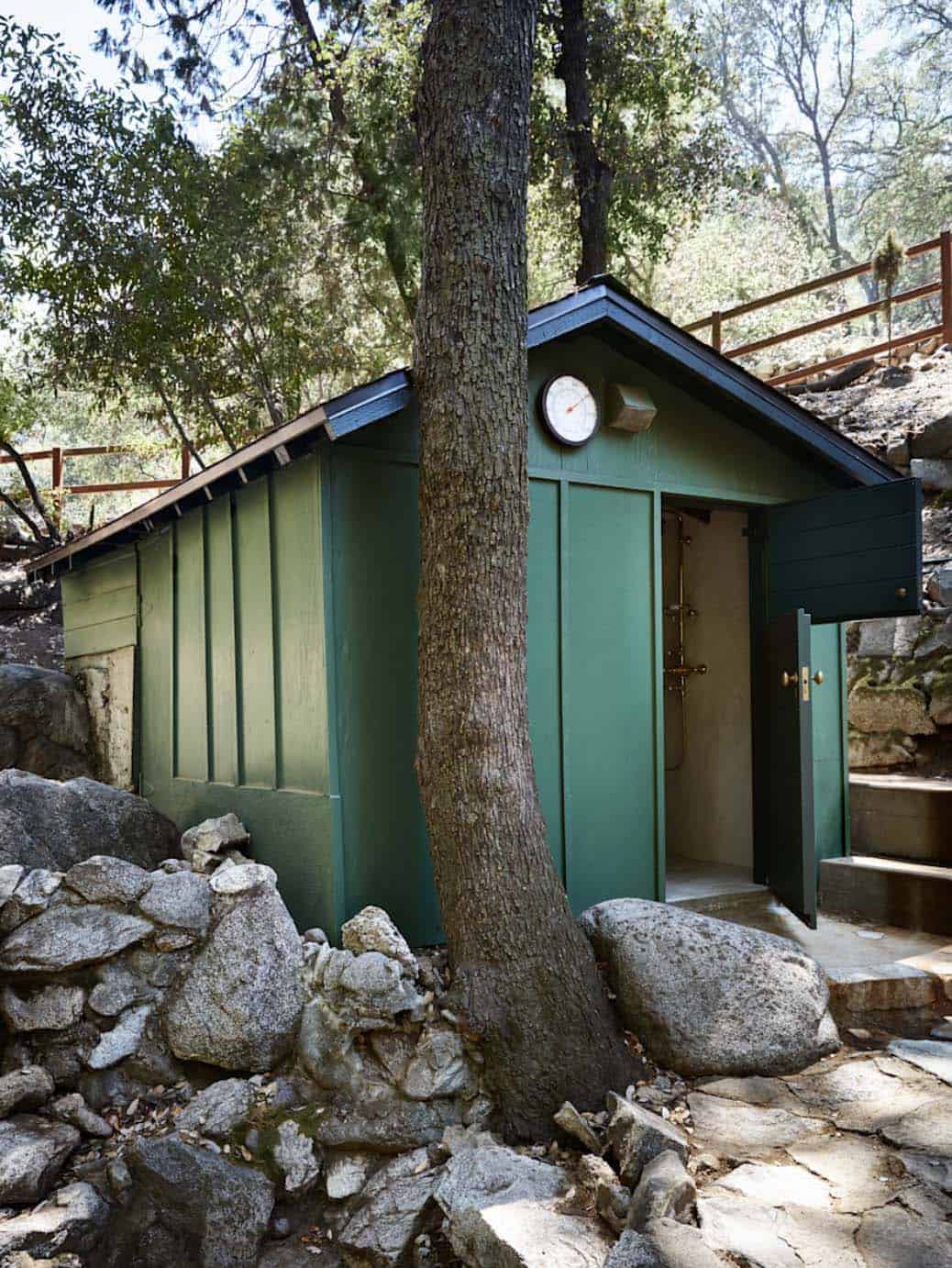 Green painted shower house with brass hardware and boulder surround