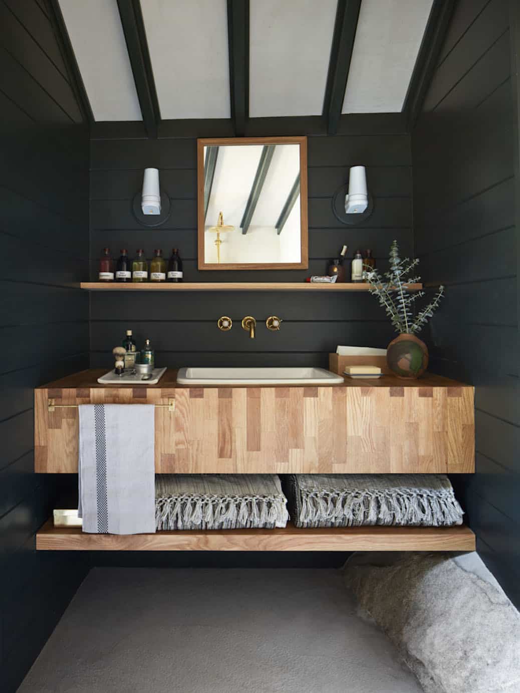 Floating butcher block vanity with brass faucet and dark shiplap walls