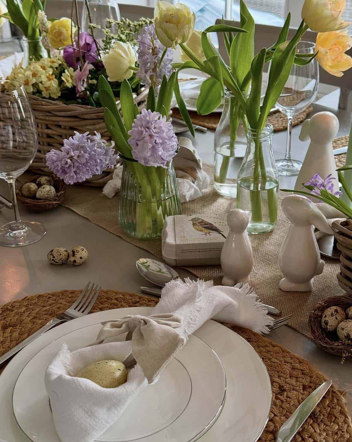 Easter table decorating idea featuring wicker baskets with spring tulips, hyacinths, and a quail egg nest