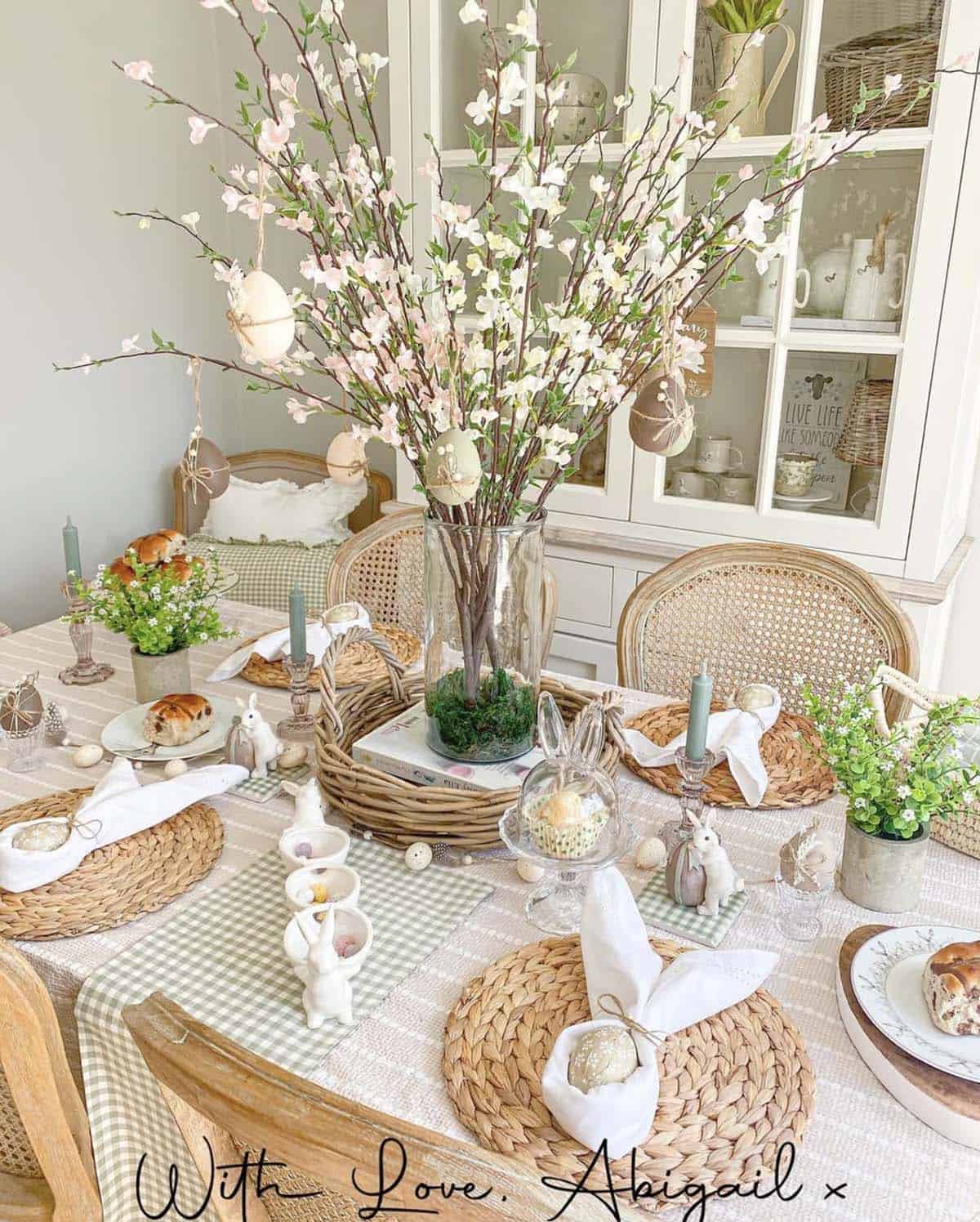 Easter table decorating idea featuring cherry blossom branch centerpiece with hanging decorated eggs