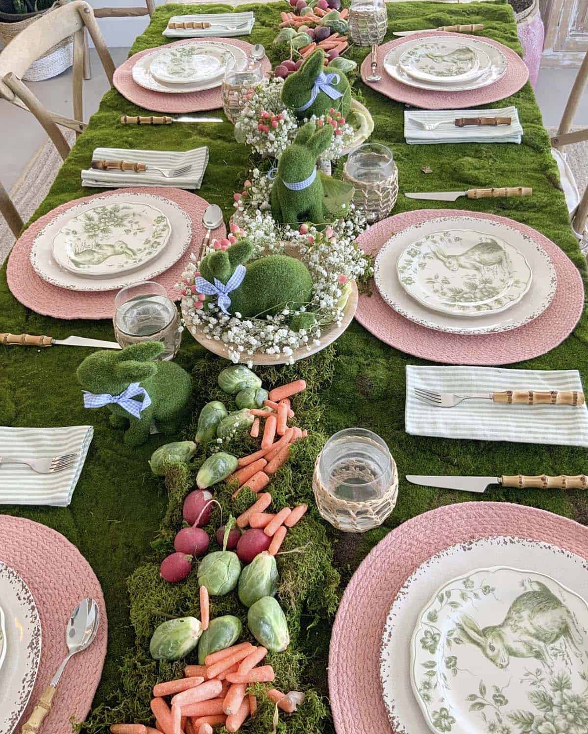 Garden Easter table with moss runner, moss bunny figurines, and fresh carrots and vegetables