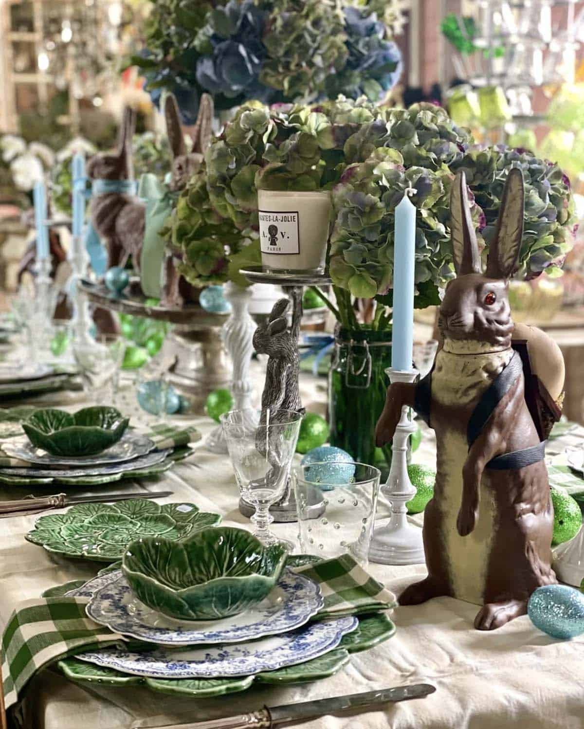 Easter tablescape with papier-m&acirc;ch&eacute; bunny centerpiece, blue hydrangeas, and cabbage leaf plates