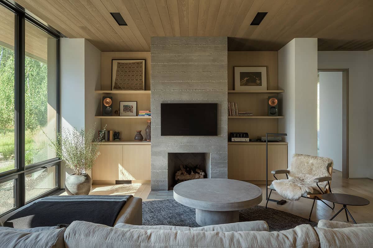 Living room with travertine fireplace, built-in oak shelving, and wood-paneled ceiling