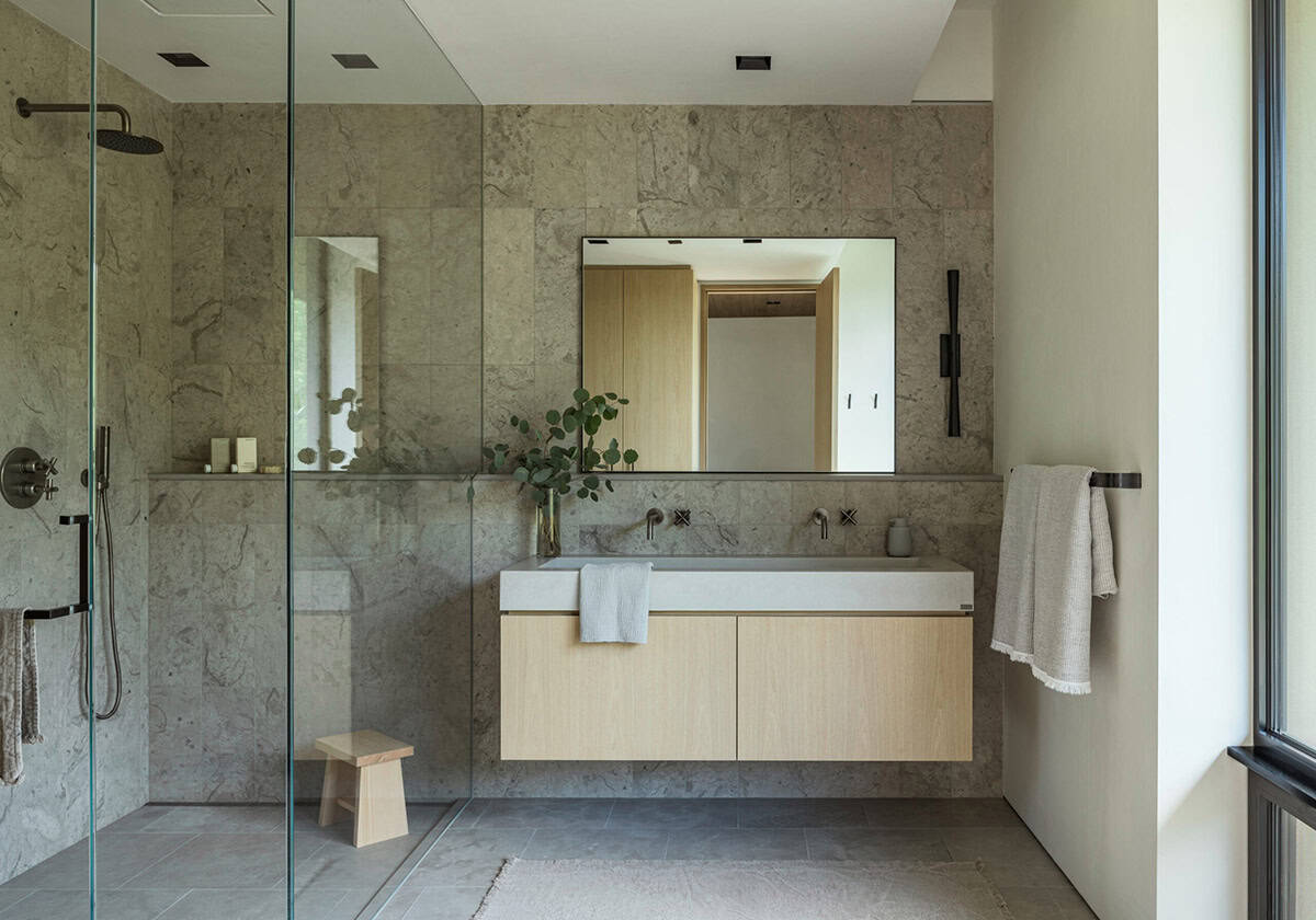 Spa-like bathroom with full-height stone tile walls, glass shower, and floating oak vanity