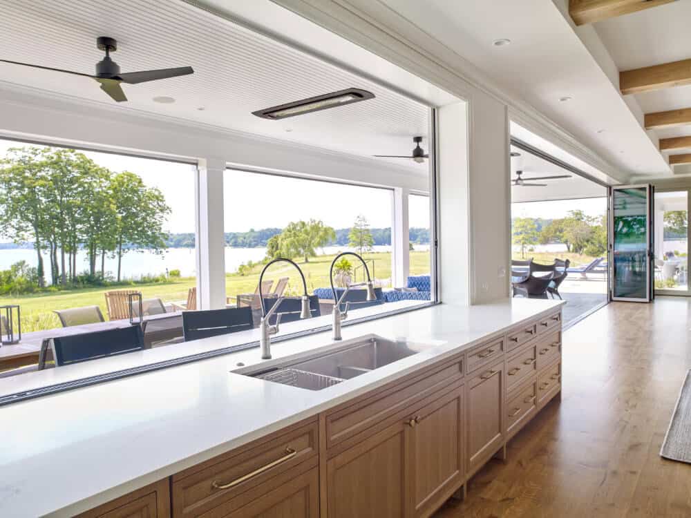 Coastal kitchen with folding window opening to exterior bar top in Maryland waterfront home
