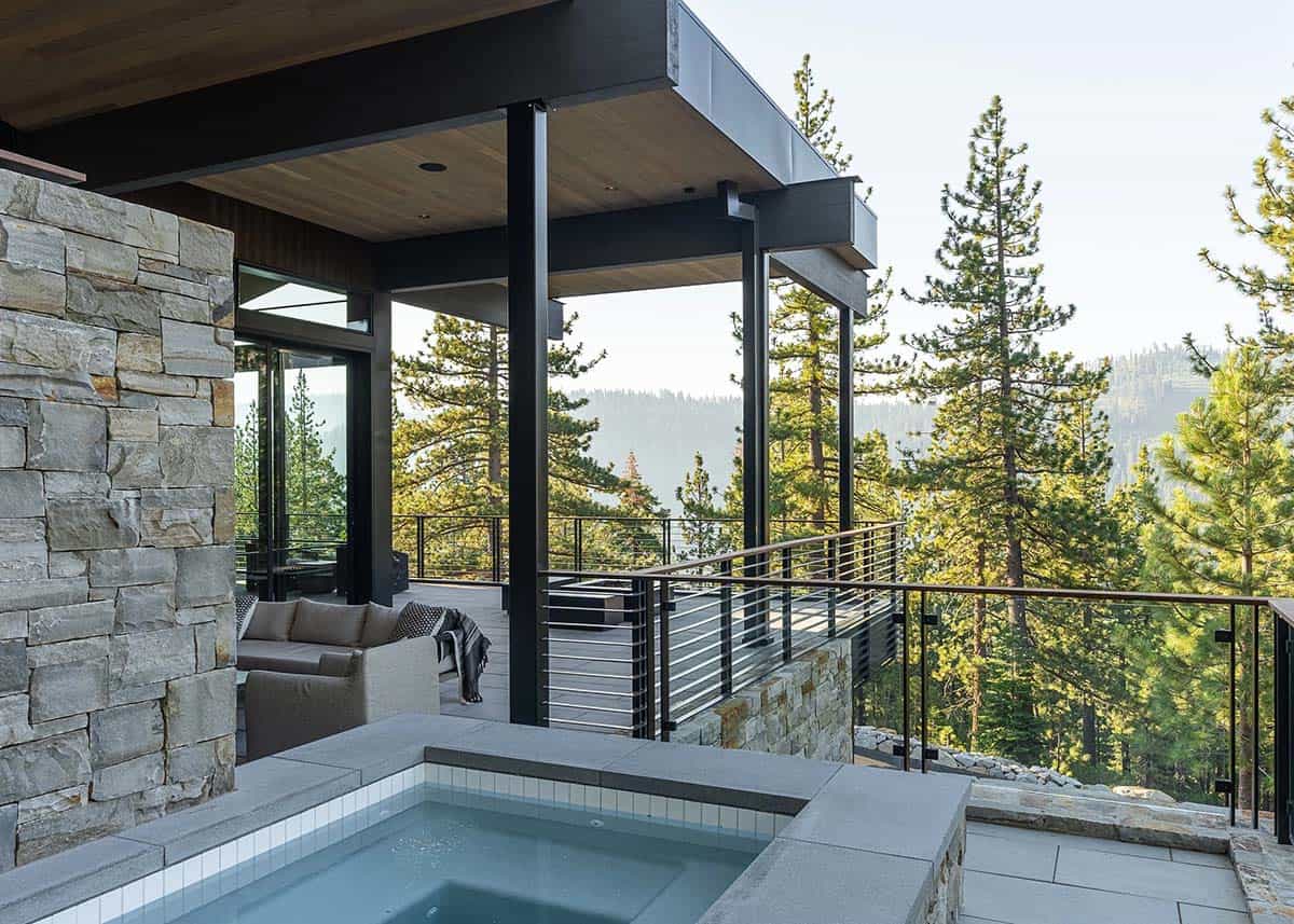 Hillside hot tub with stone surround and pine forest mountain views