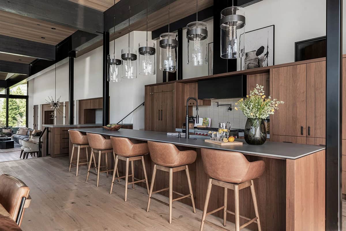 Open-plan kitchen with long island, leather bar stools, and pendant lights