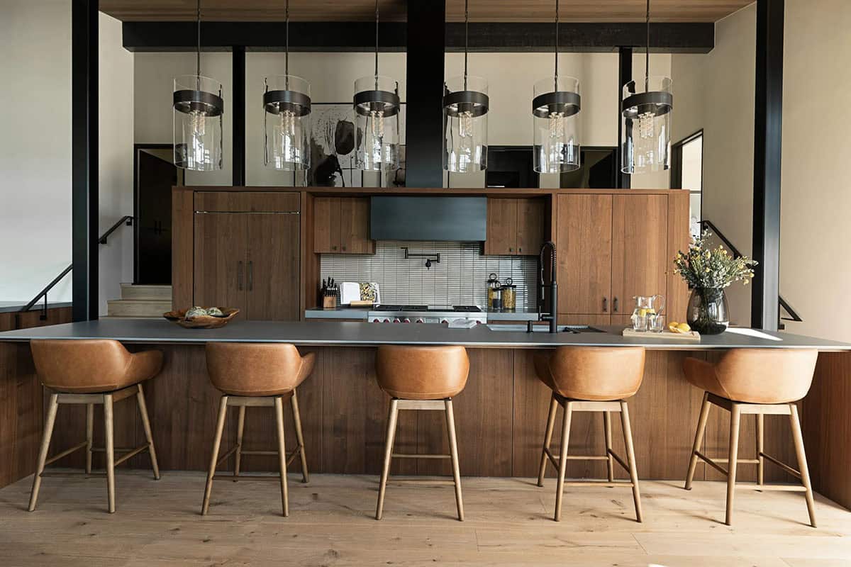 Kitchen island with cognac leather stools and glass cylinder pendant lights