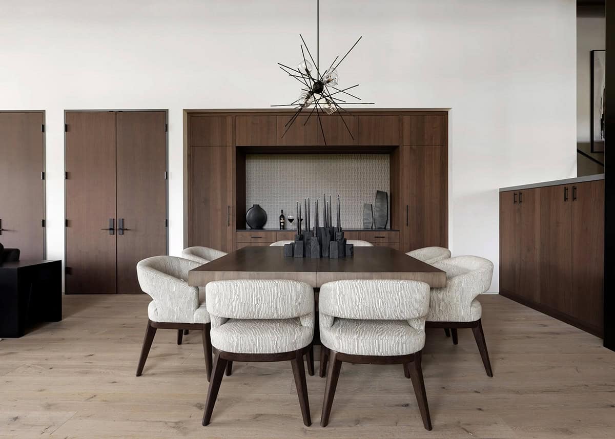 Dining room with curved cream chairs, walnut sideboard, and starburst chandelier