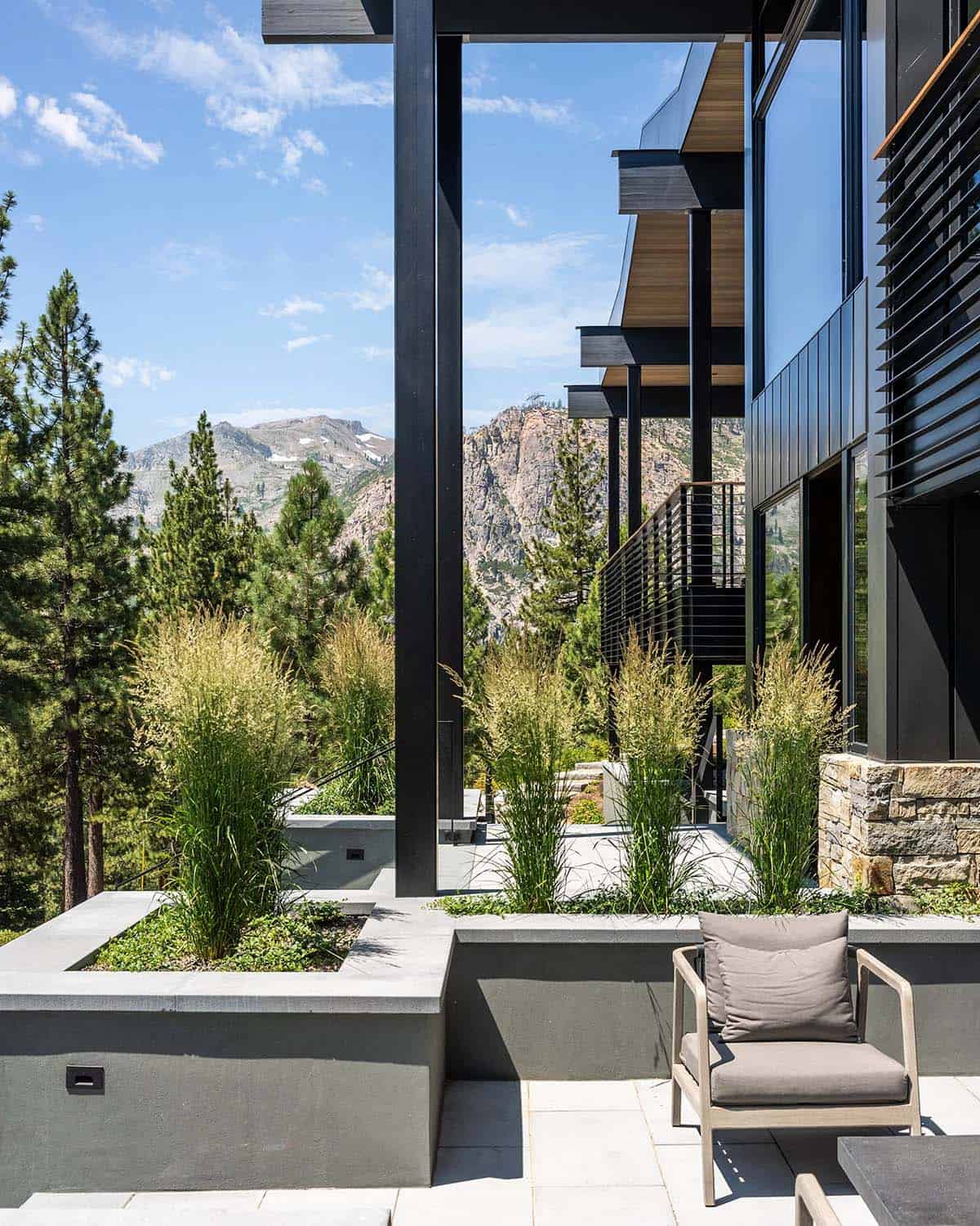 Terraced patio with ornamental grasses, concrete planters, and rocky mountain backdrop