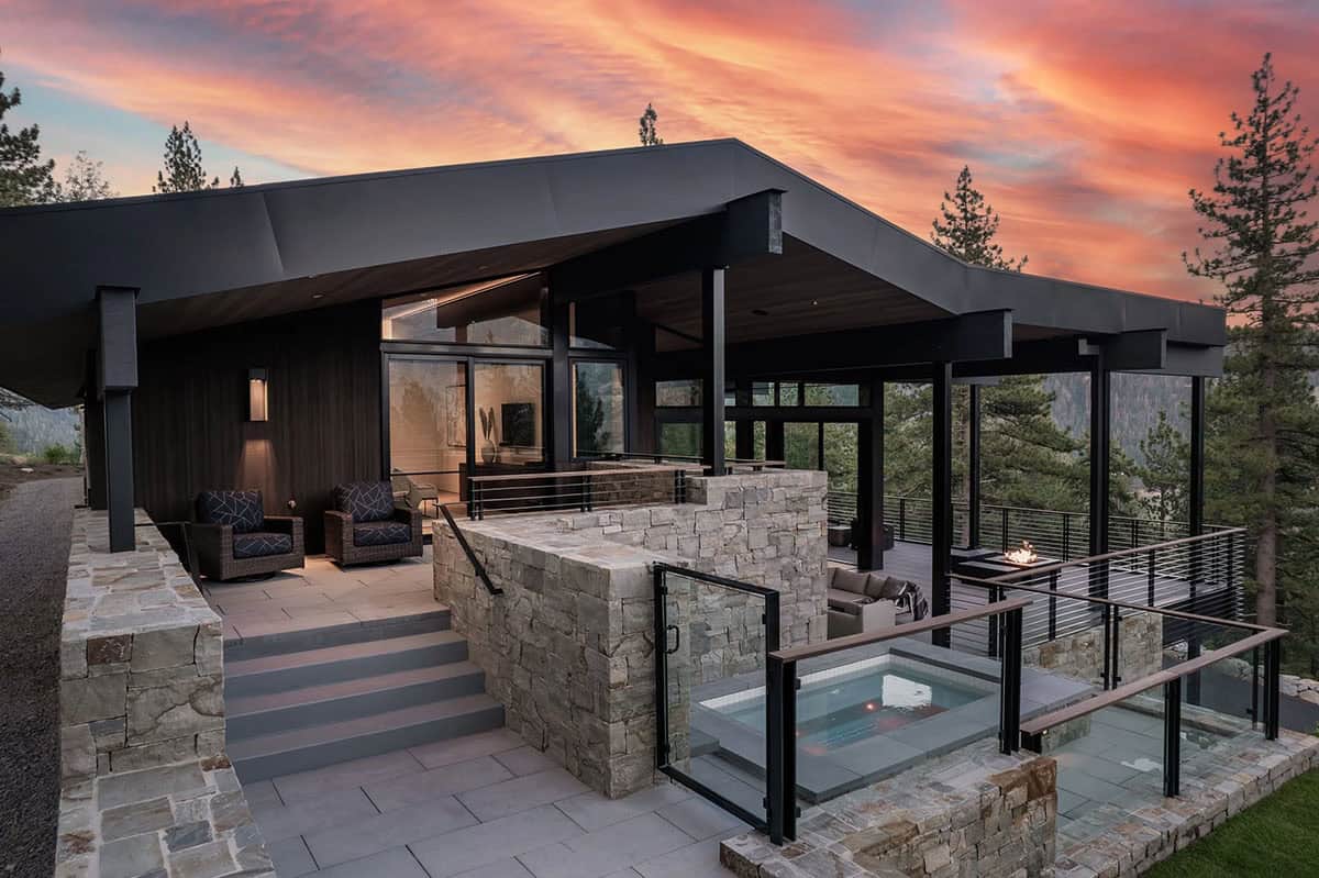 Modern mountain home exterior at sunset with spa, fire pit deck, and vivid sky