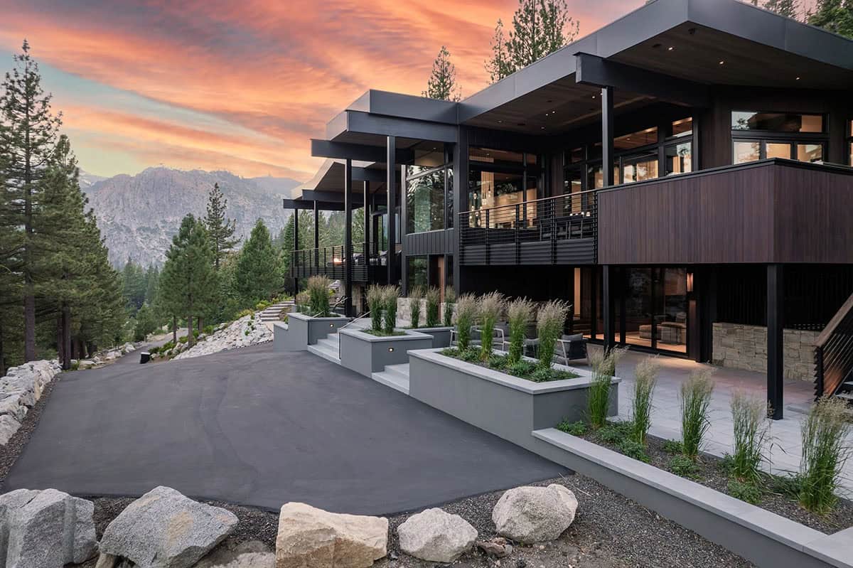 Ski retreat front exterior at sunset with cantilevered rooflines and mountain backdrop