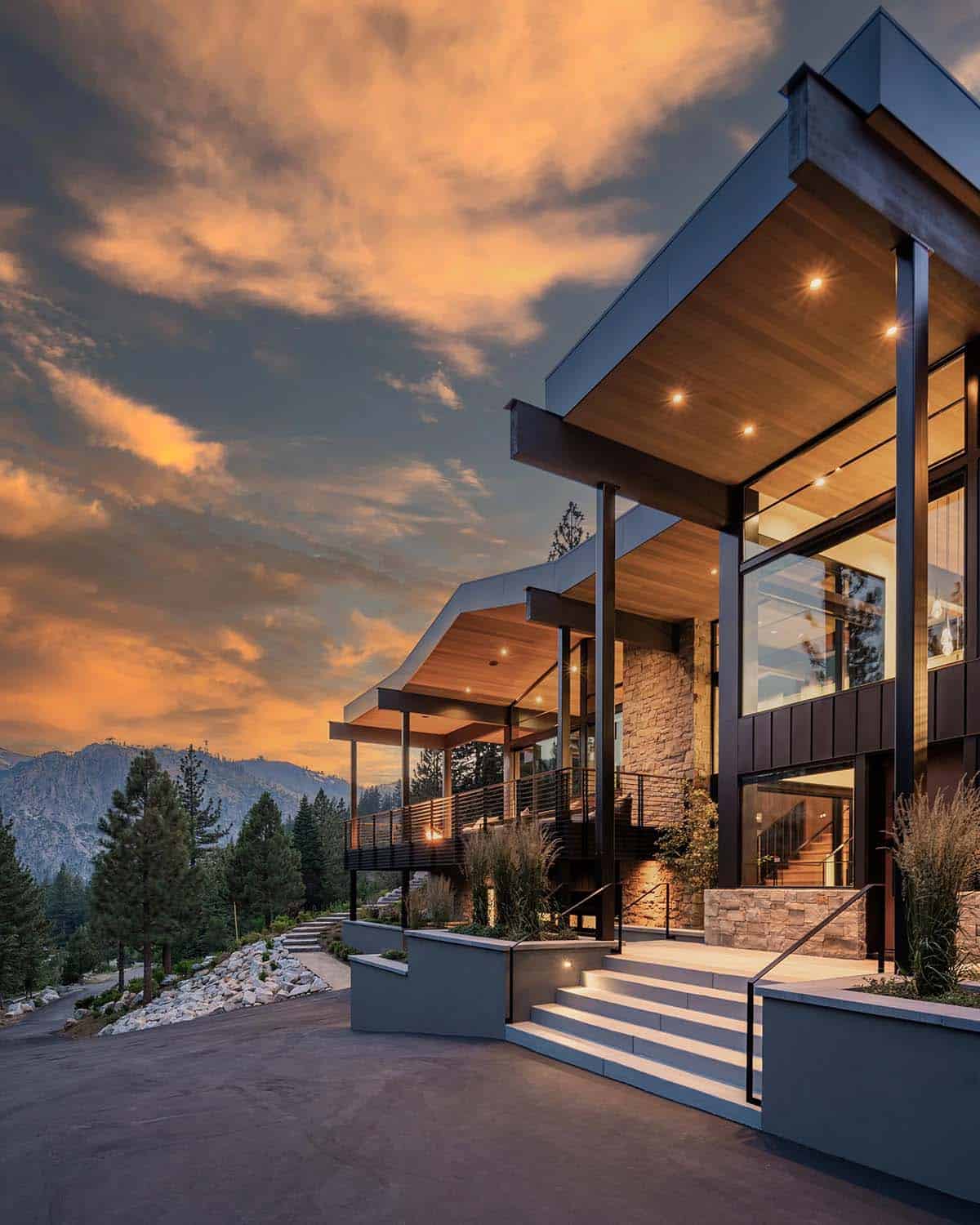 Side exterior at dusk with cantilevered rooflines, stone entry steps, and mountain backdrop