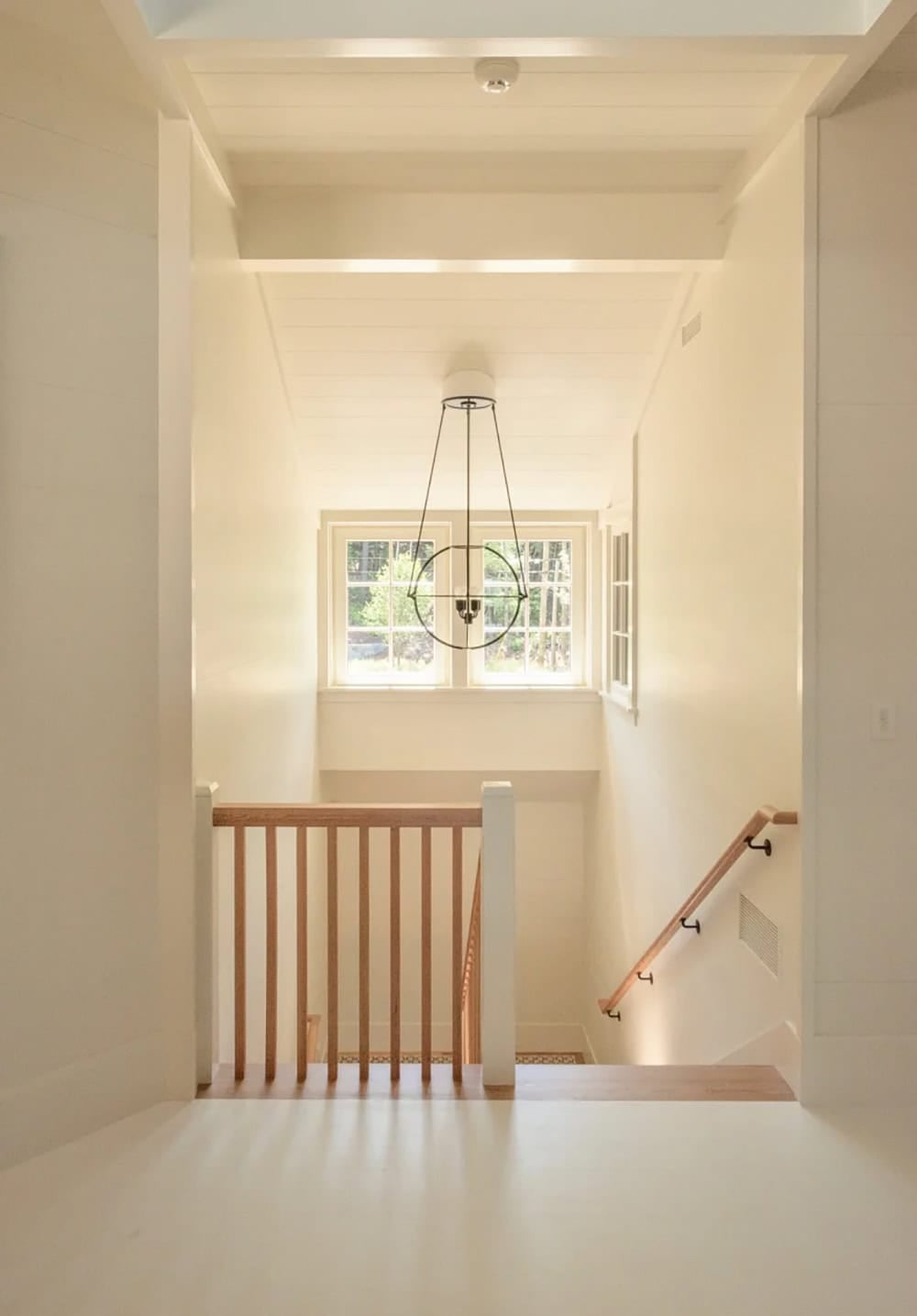 Exterior entry detail of the Lake Sunapee New Hampshire lake house showing the natural stone foundation, cedar shingle siding transition, and timber bracket details beneath a covered porch roof
