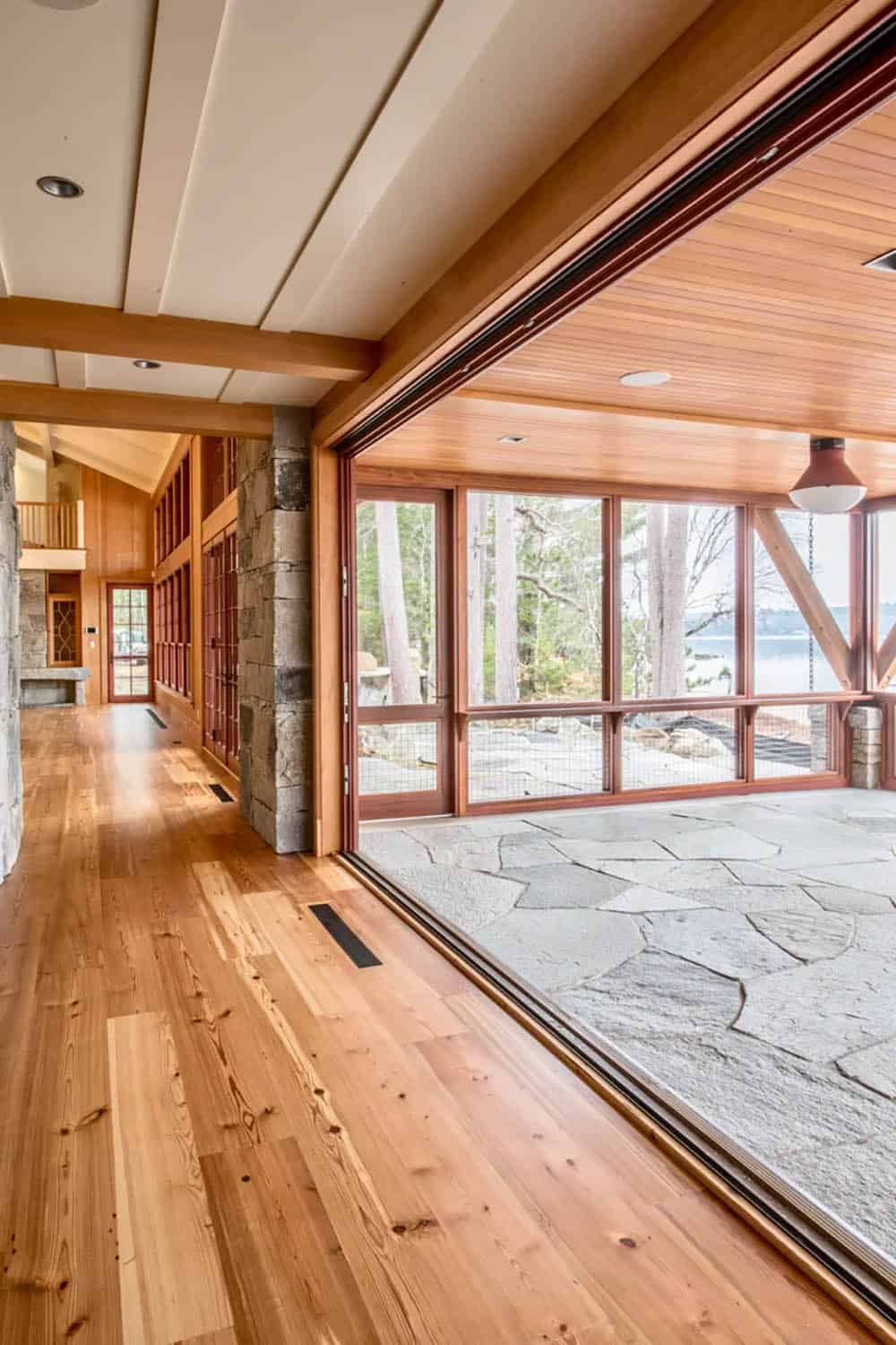 Screened porch of the Lake Sunapee New Hampshire lake house &mdash; wicker and painted wood furniture, ceiling fan, painted bead-board ceiling, and full lake views through the screened openings