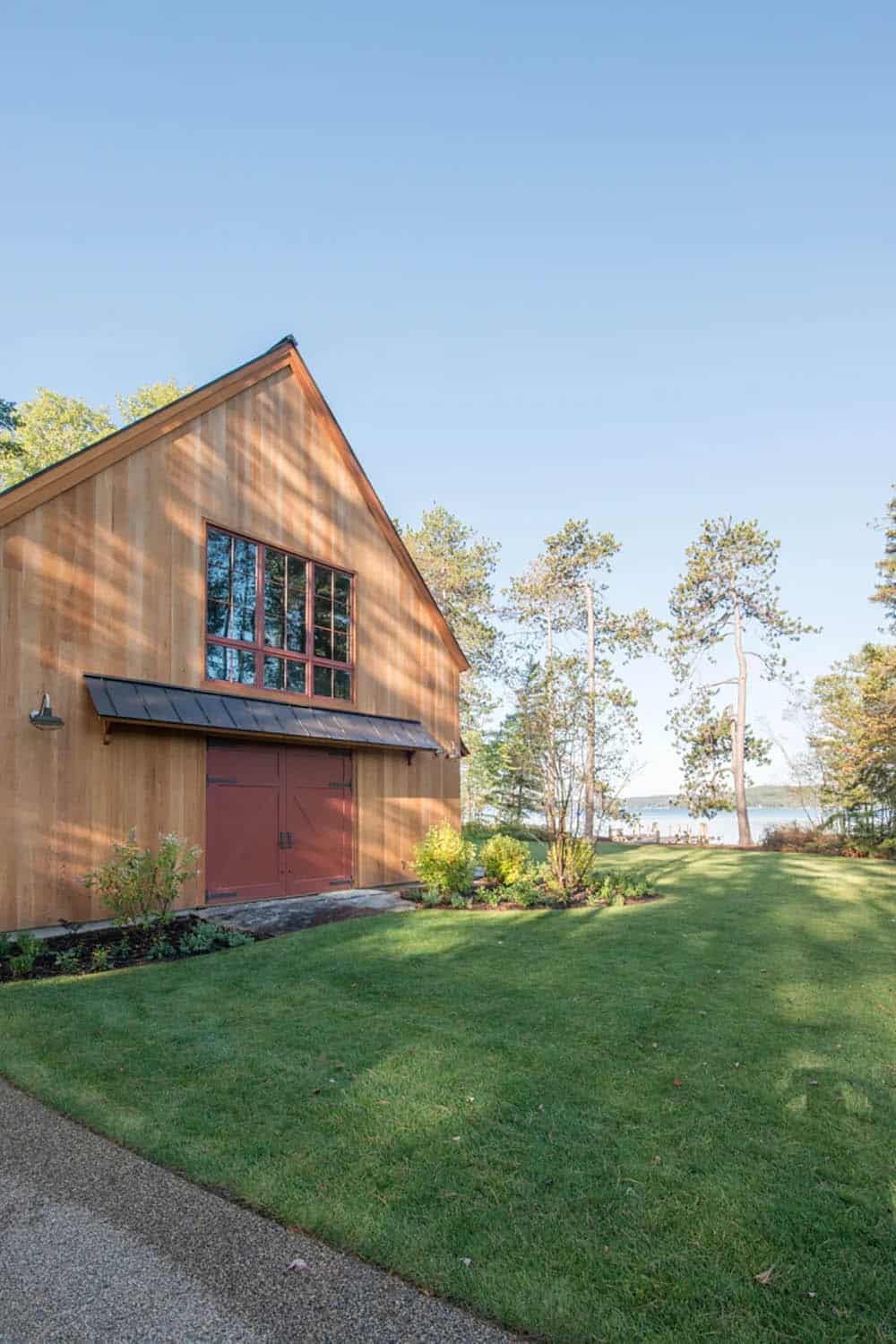 Exterior of the Lake Sunapee New Hampshire lake house viewed from the water &mdash; shingle-style architecture framed by native trees and native plantings introduced by Pellettieri Associates landscape design