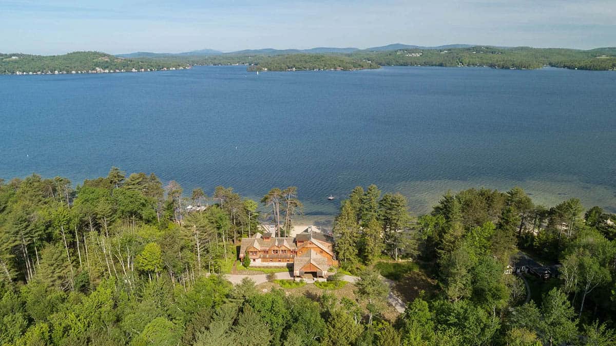 Second aerial view of the Lake Sunapee lakefront property in Newbury, New Hampshire &mdash; showing the full 3.5-acre site, the relocated private road, the new two-acre meadow, and the relationship of all three structures to the private sandy beach and lake