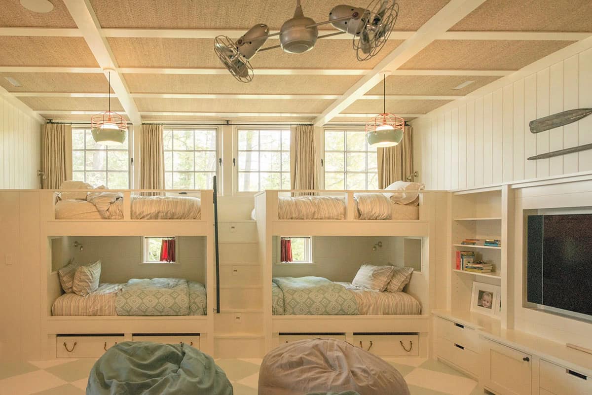 Bunk bedroom of the Lake Sunapee summer house &mdash; custom built-in bunk beds with storage drawers below, painted wood paneling, and plaid and striped bedding giving the room a classic New England summer camp feeling