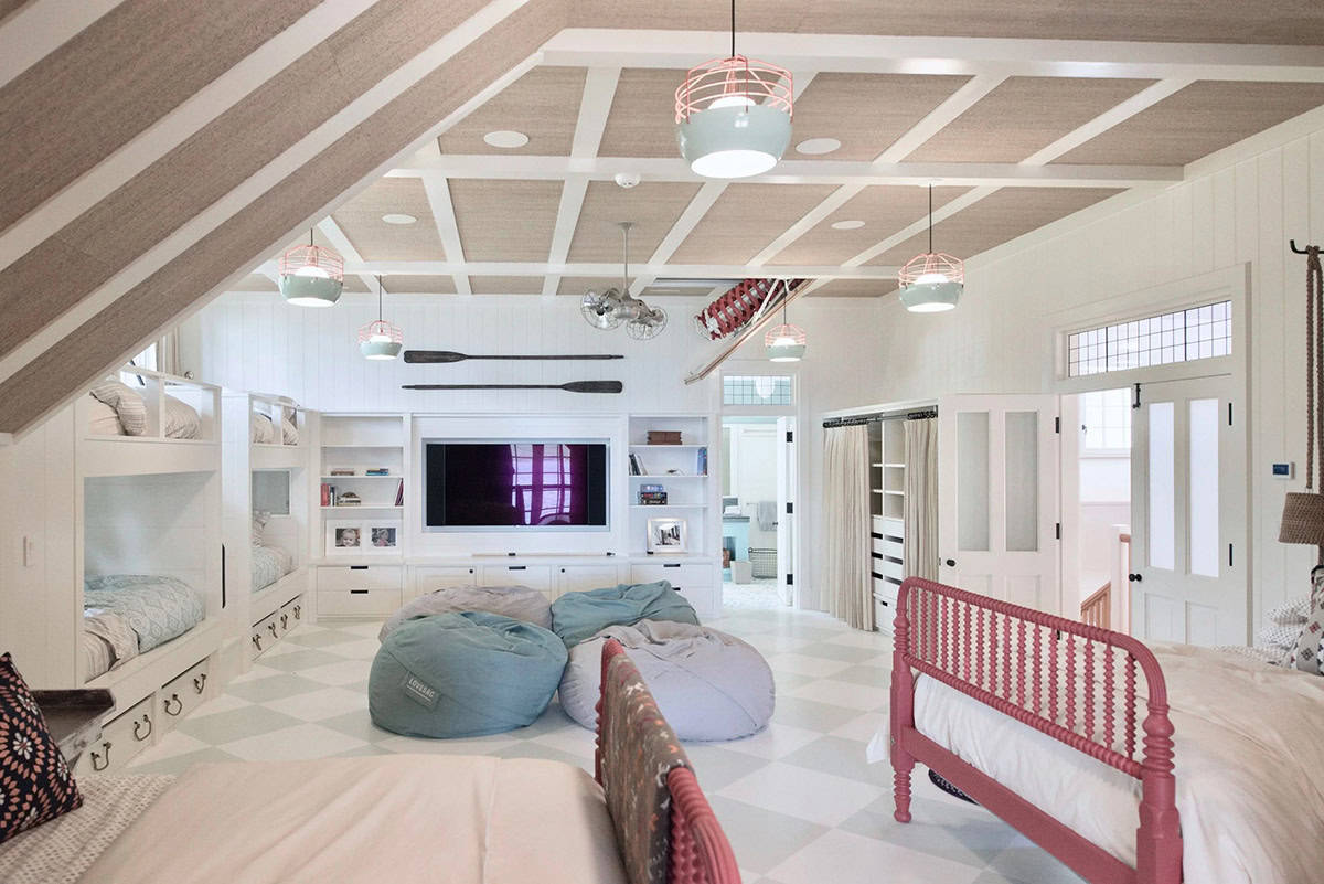 Wide view of the children's bunk room and family room on the upper level of the Lake Sunapee New Hampshire lake house &mdash; built-in bunk beds along two walls, painted surfaces, and casual furniture for games and relaxing