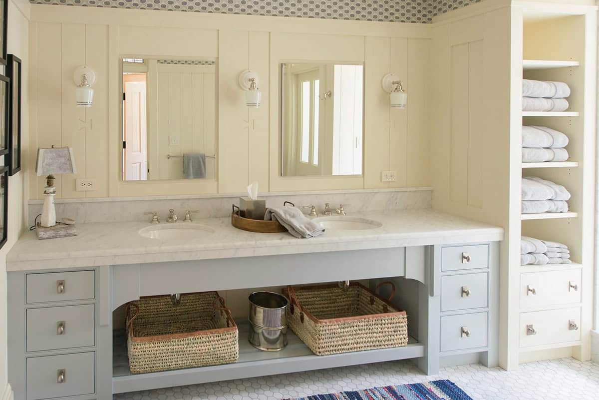 Bathroom vanity detail in the Lake Sunapee New Hampshire lake house &mdash; a painted wood vanity with a marble or stone countertop, a traditional mirror, and classic fixtures with a warm, collected aesthetic