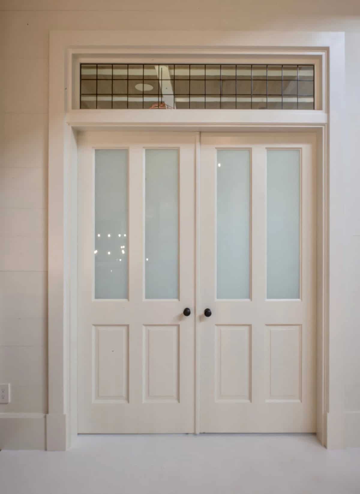 Entry door to the bunk bedroom in the Lake Sunapee New Hampshire lake house &mdash; a painted wood door with playful nautical hardware leading into the children's wing upstairs