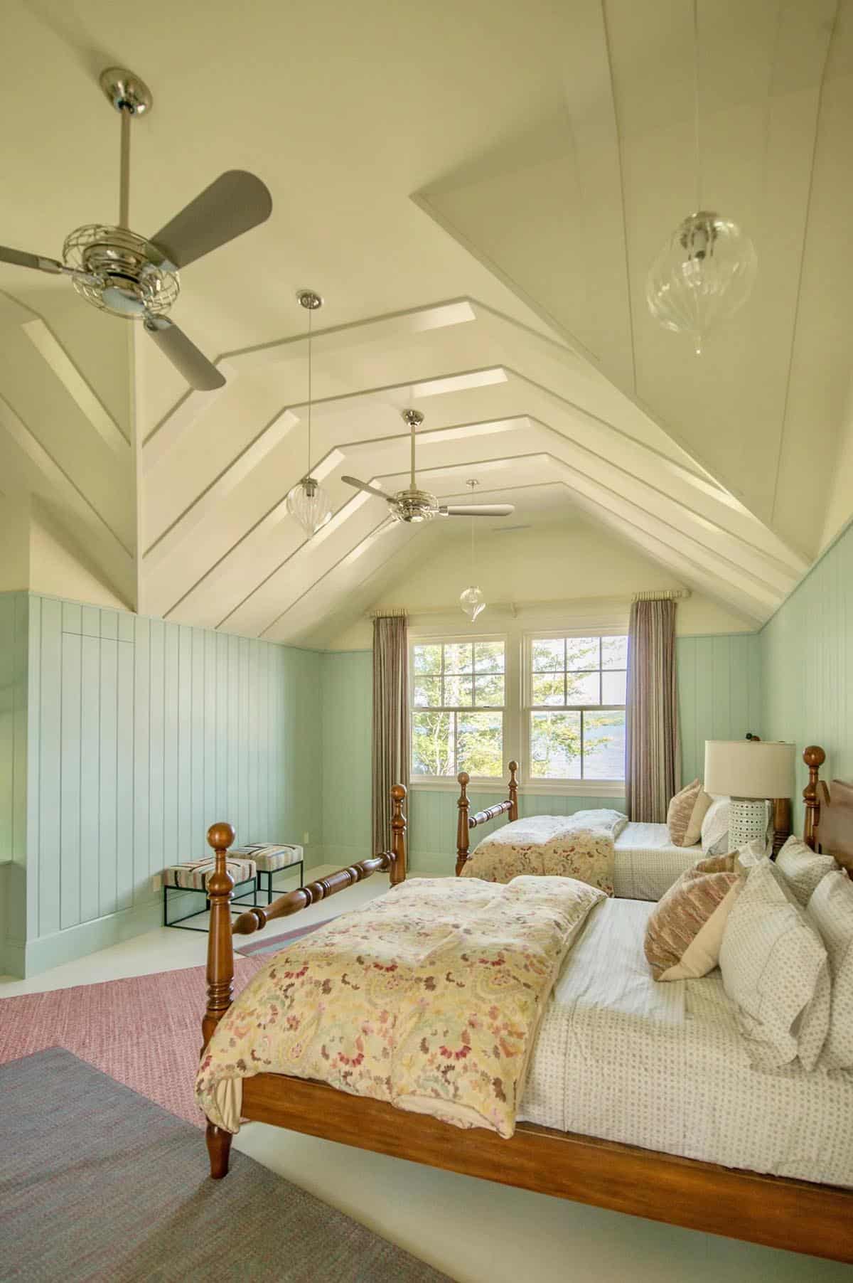Bedroom with an antique iron or wood bed, a sleeping niche with built-in shelving, and plaid or striped bedding evoking the nostalgic atmosphere of a New England summer lake house
