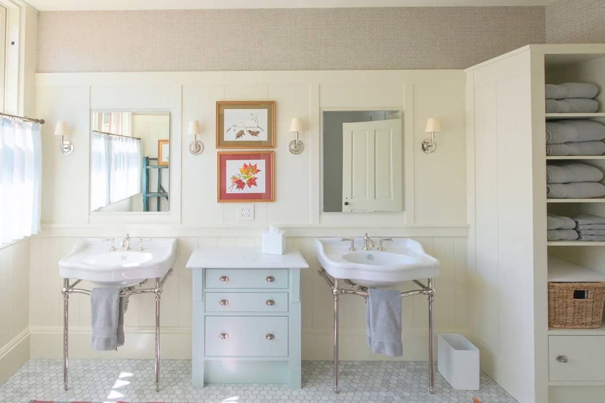 Second bathroom with traditional finishes &mdash; painted bead-board wainscoting, marble tile floor, a pedestal or painted vanity, and warm natural light from a frosted window, Lake Sunapee New Hampshire