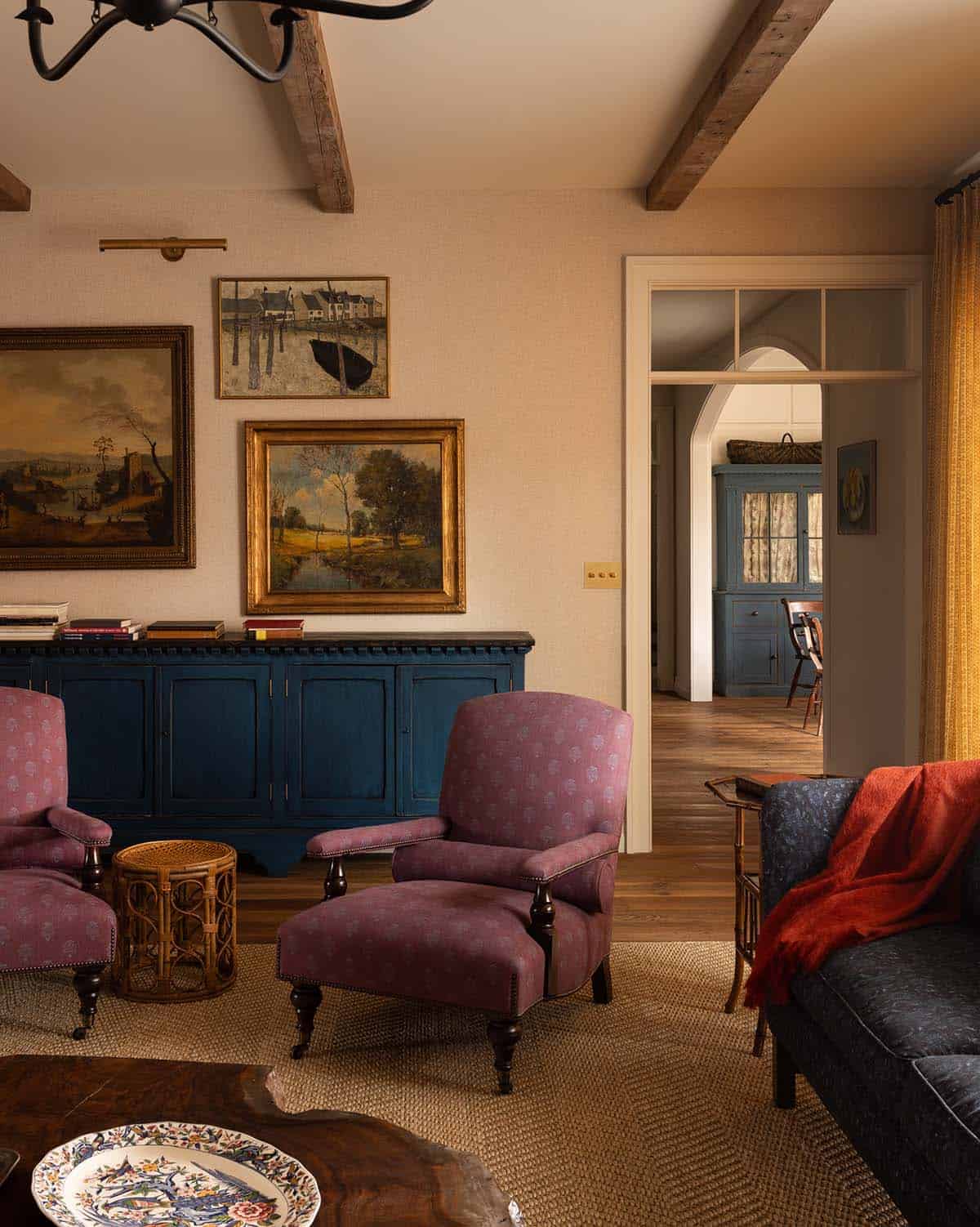 living room with plum armchairs, blue sideboard, and antique landscape paintings, Colorado equestrian home