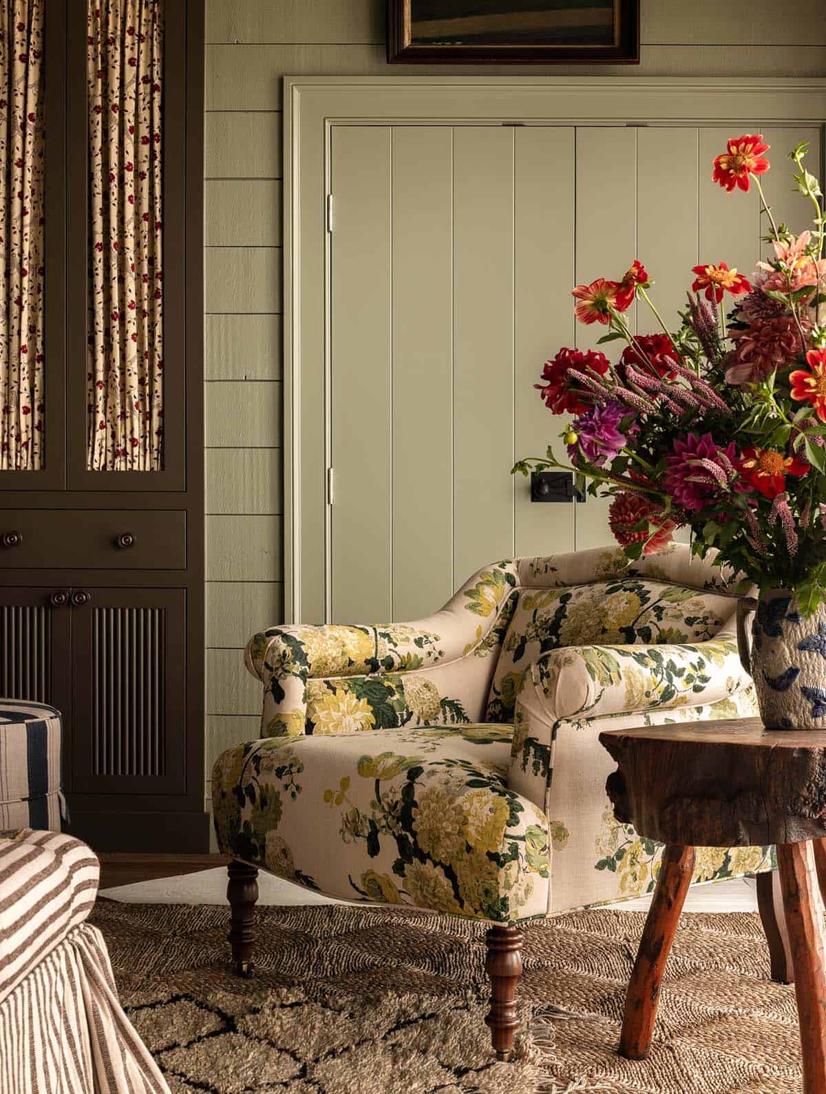 sitting room with floral armchair and bold flower arrangement against green paneled wall, Colorado equestrian home