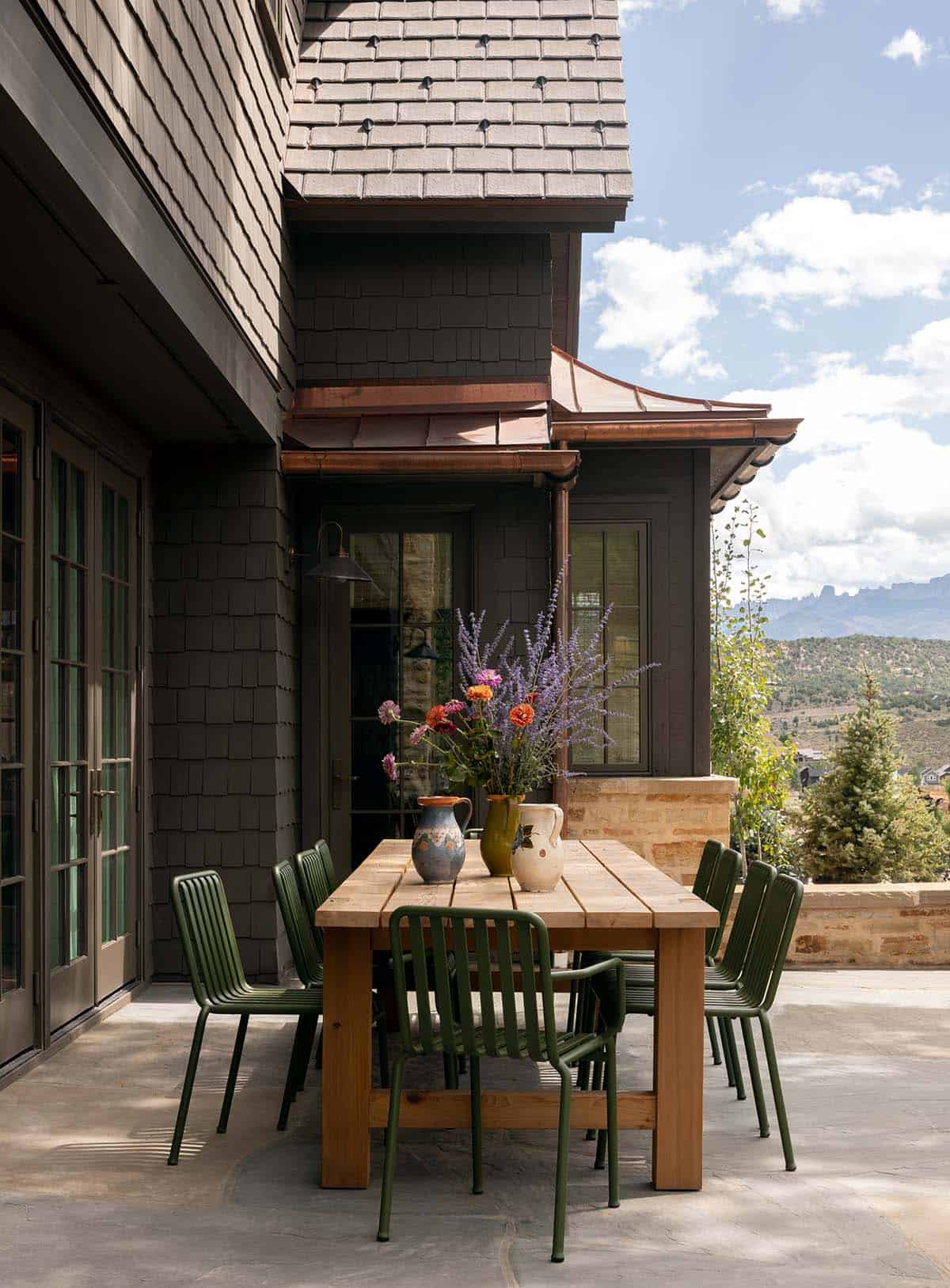 outdoor patio dining area with wood table, green chairs, and San Juan Mountain views, Colorado equestrian home