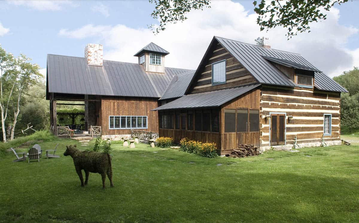 Rustic log cabin and barn retreat with metal roof, screened porch, and topiary bear sculpture on lawn