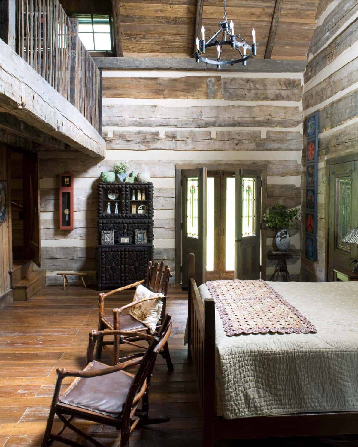 Log cabin bedroom with twig chairs, carved black cabinet, stained glass doors, and iron chandelier